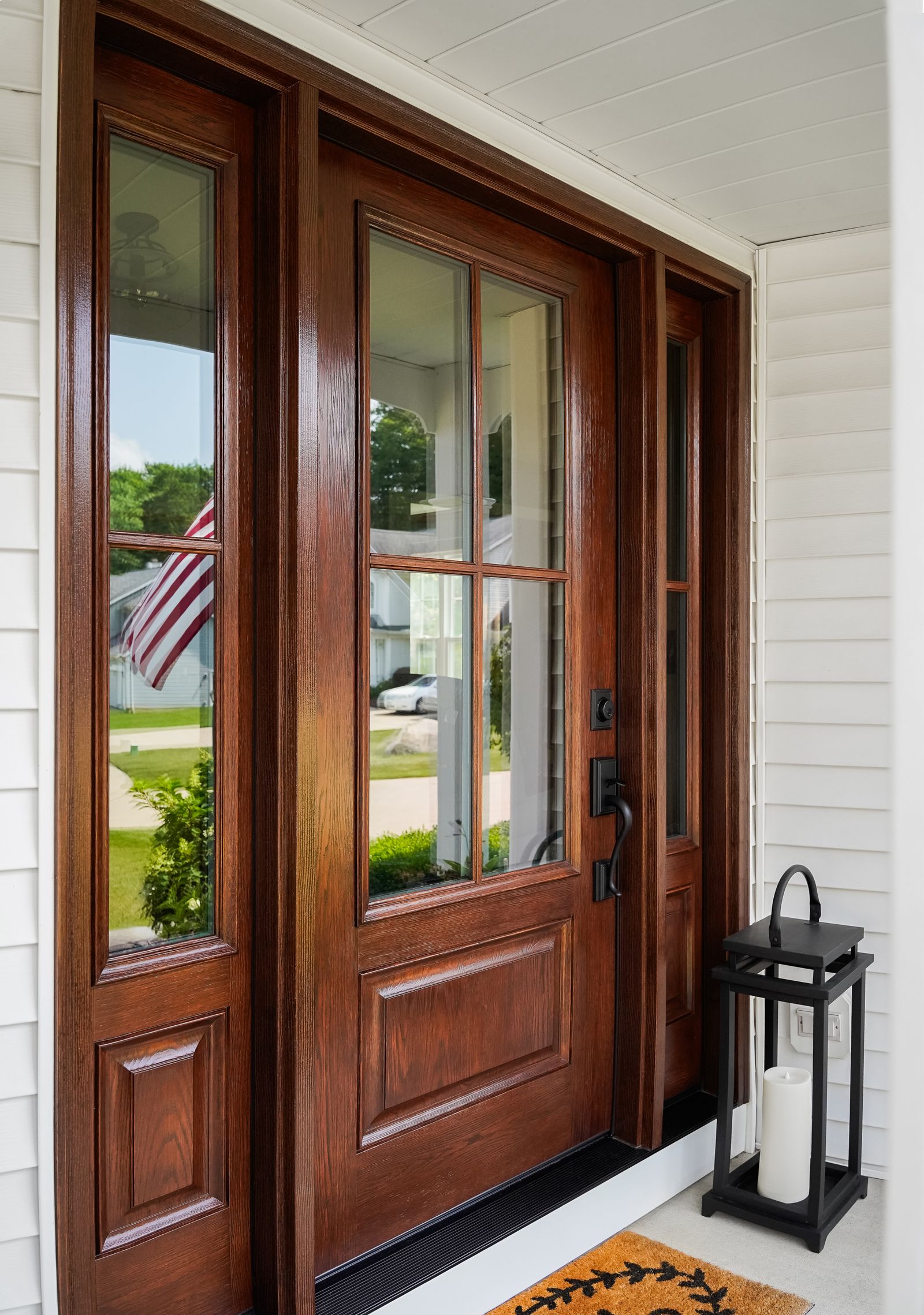 Stained fiberglass entry door with sidelights on a covered porch